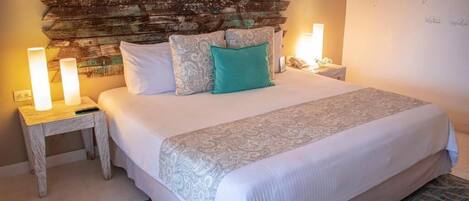 Un lit bien fait, avec une literie à motifs, une tête de lit rustique, des lampes de chevet et un mur décoratif orné d’une citation.