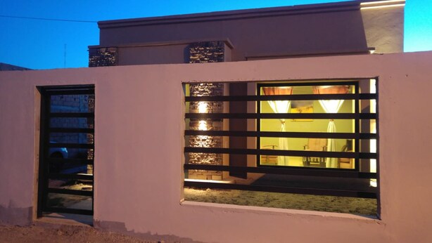 A modern building with a large window and a door. - Casa Gobernador Gregores Patagonia (Gobernador Gregores)