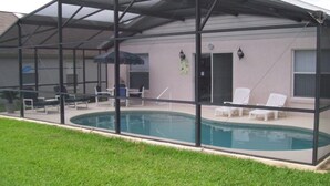 A covered swimming pool with lounge chairs and a patio area. - 4BR 3BA Home in Indian Creek by CV-2653 (Kissimmee)