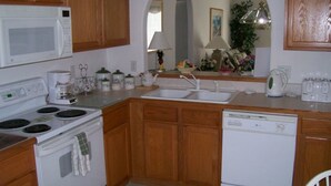 A kitchen with wooden cabinets, a microwave, stove, sink, and dishwasher. - 4BR 3BA Home in Indian Creek by CV-2653 (Kissimmee)
