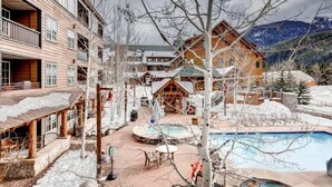 A resort with a pool, wooden buildings, and a mountainous backdrop. - River Run Village 2 Bedroom Condo - 100 yards to slopes, Pool, Hot Tub Access (Keystone)