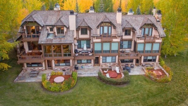 A large, multi-story house with a prominent balcony, surrounded by lush greenery and autumn foliage. - Snowmass Owl Creek 9904 (Snowmass Village)