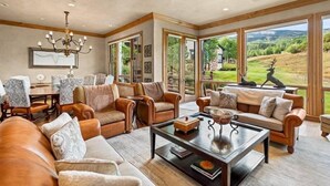A spacious living room with leather sofas, a coffee table, and large windows offering a view of the outdoors. - Snowmass Owl Creek 9904 (Snowmass Village)