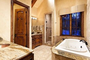 A bathroom with a wooden door, a shower, a large window with a view of trees, and a white bathtub. - Snowmass Castle Hill (Snowmass Village)