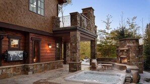 A stone exterior with a hot tub, outdoor seating, and a fireplace. - Snowmass Castle Hill (Snowmass Village)