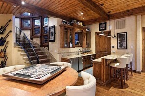 A spacious kitchen with wooden cabinets, a built-in island, and a dining area with bar stools. - Snowmass Castle Hill (Snowmass Village)