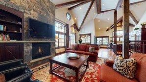 Una sala de estar amplia con chimenea de piedra, televisor, un conjunto de sofás y una mesa de centro.