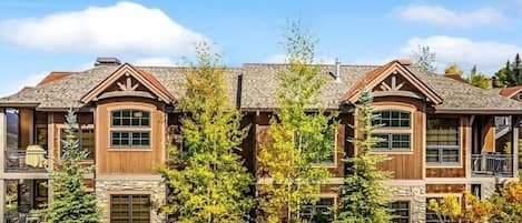 A multi-story house with a stone facade, large windows, and a balcony.