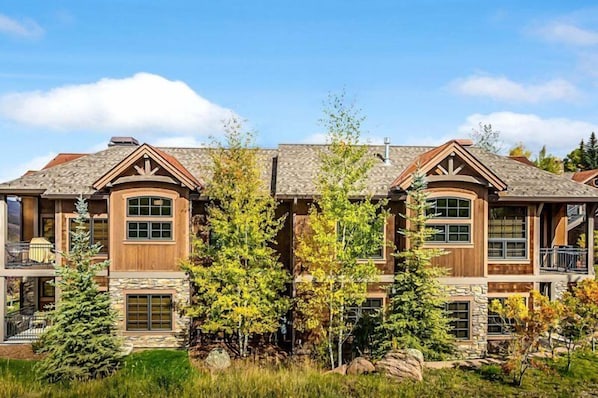 A multi-story house with a stone facade, large windows, and a balcony.