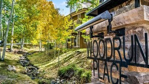 Letrero que dice "WOODRUN PLACE", con un muro de piedra y un arroyo al fondo.