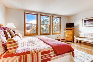 A bedroom with a bed, a chair, a dresser, and a TV.