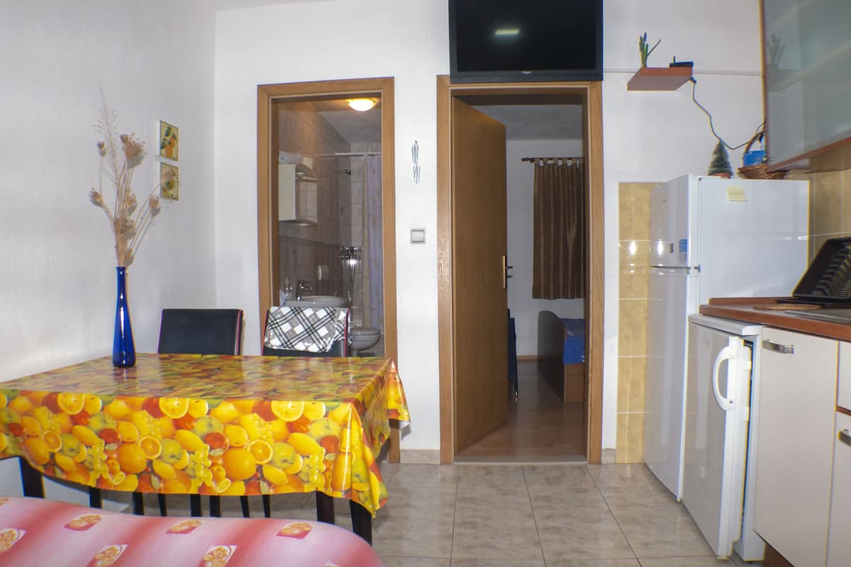 A compact kitchen with a dining table, a washing machine, and a television above the counter.