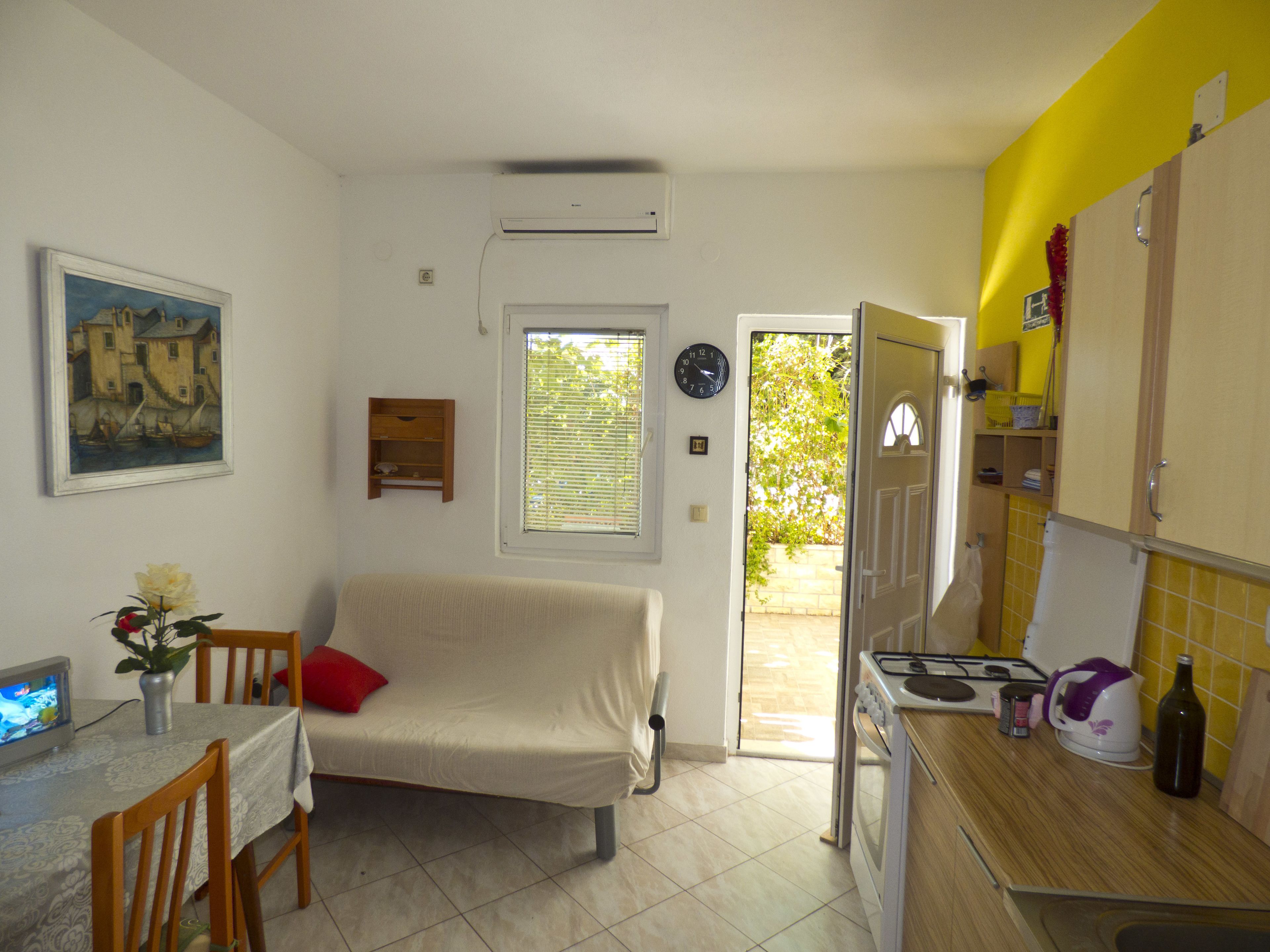 A compact living space with a kitchenette, a dining area, and a sofa.