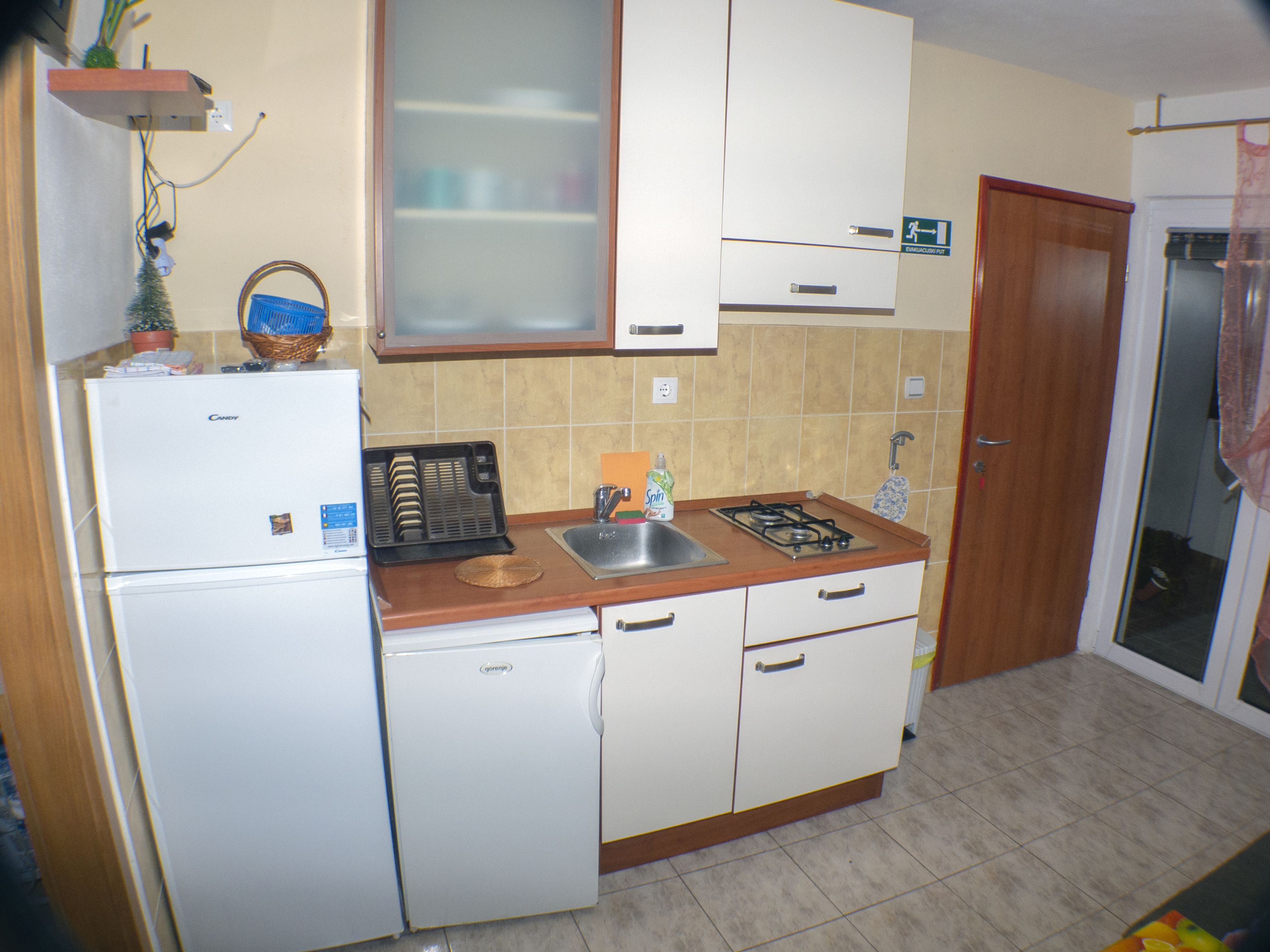 A compact kitchen with a refrigerator, stove, sink, and cabinets.