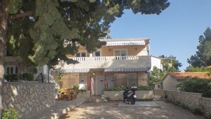 A two-story building with a stone facade, a balcony, and a covered patio area. - Apartments Plaza (Jelsa)