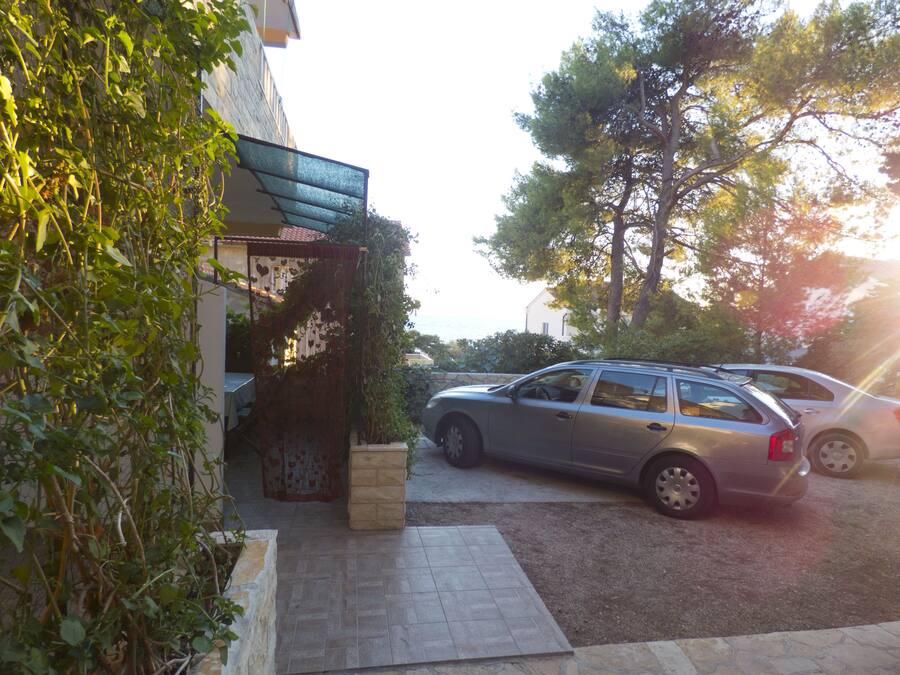Cot estacionat a la calçada, amb un mur de pedra i una tanca metàl·lica a l'esquerra.