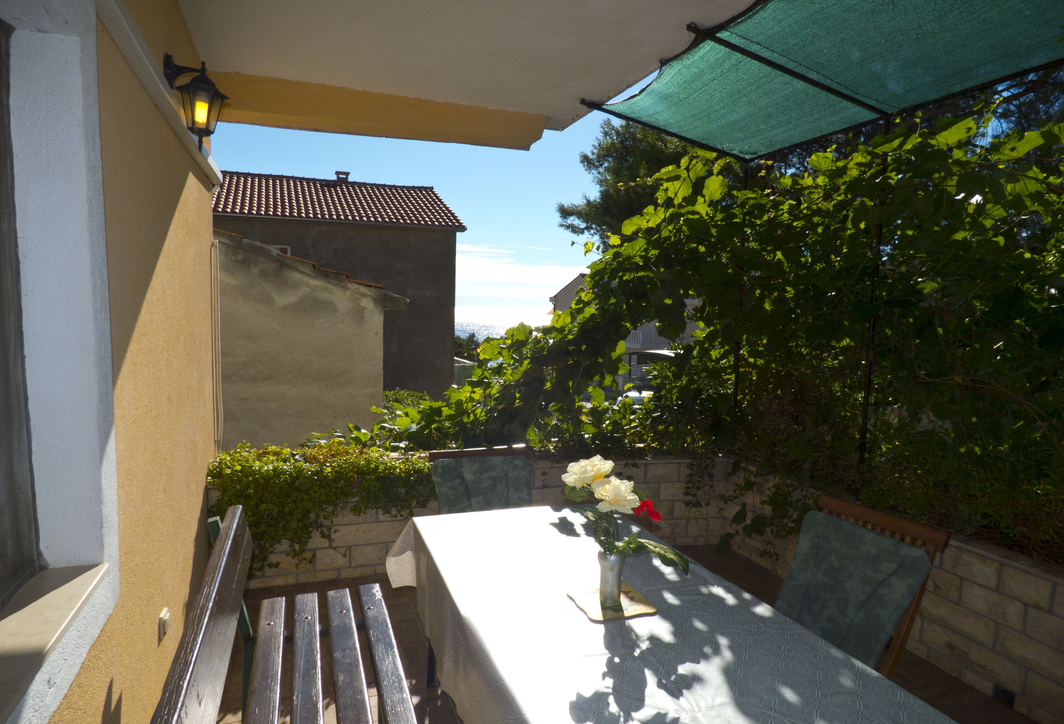 Eine Terrasse im Freien mit Tisch, Stühlen und einem Blumenvasen.