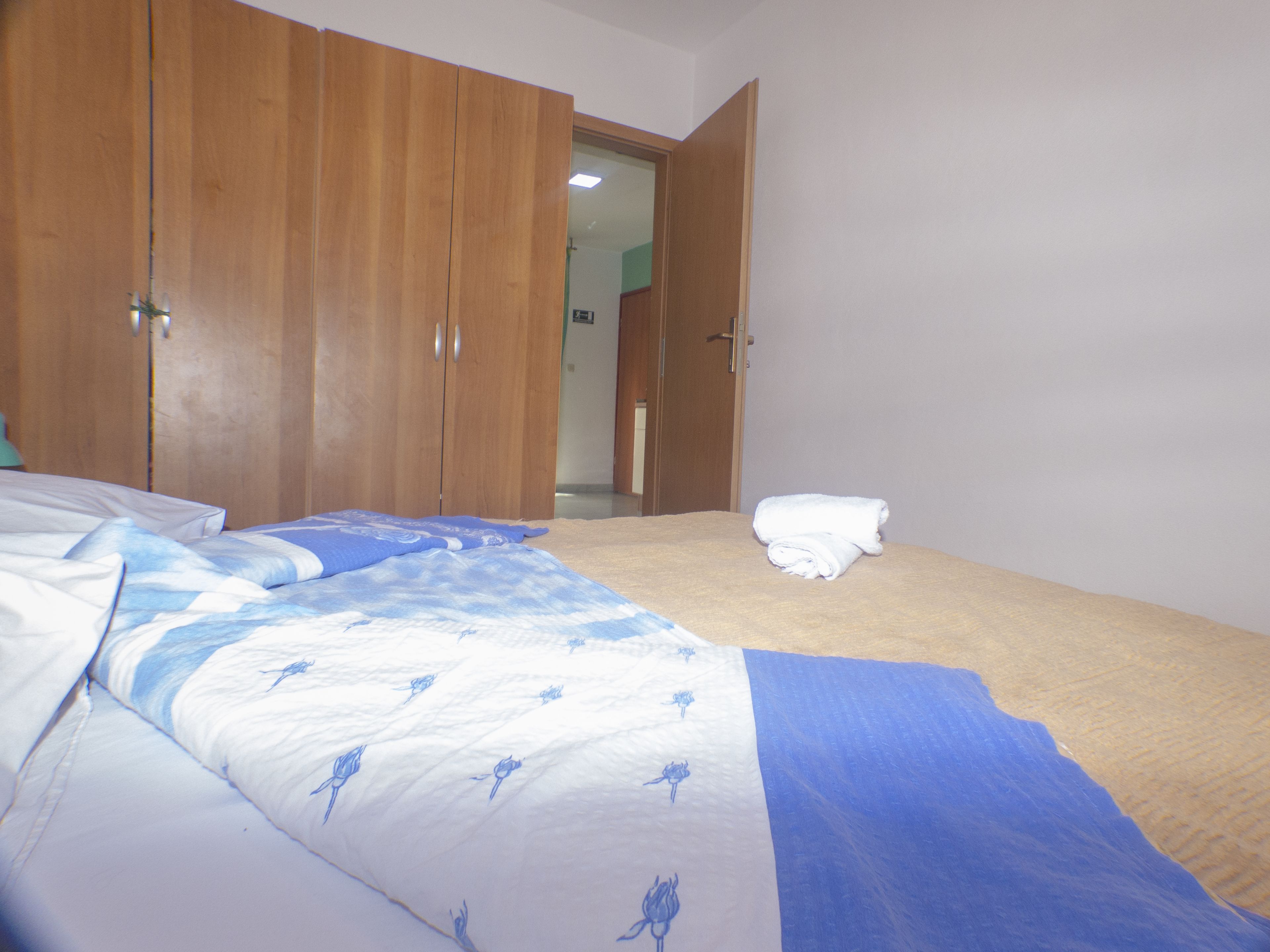 A bedroom with a bed, a wardrobe, and a bathroom visible through an open door.