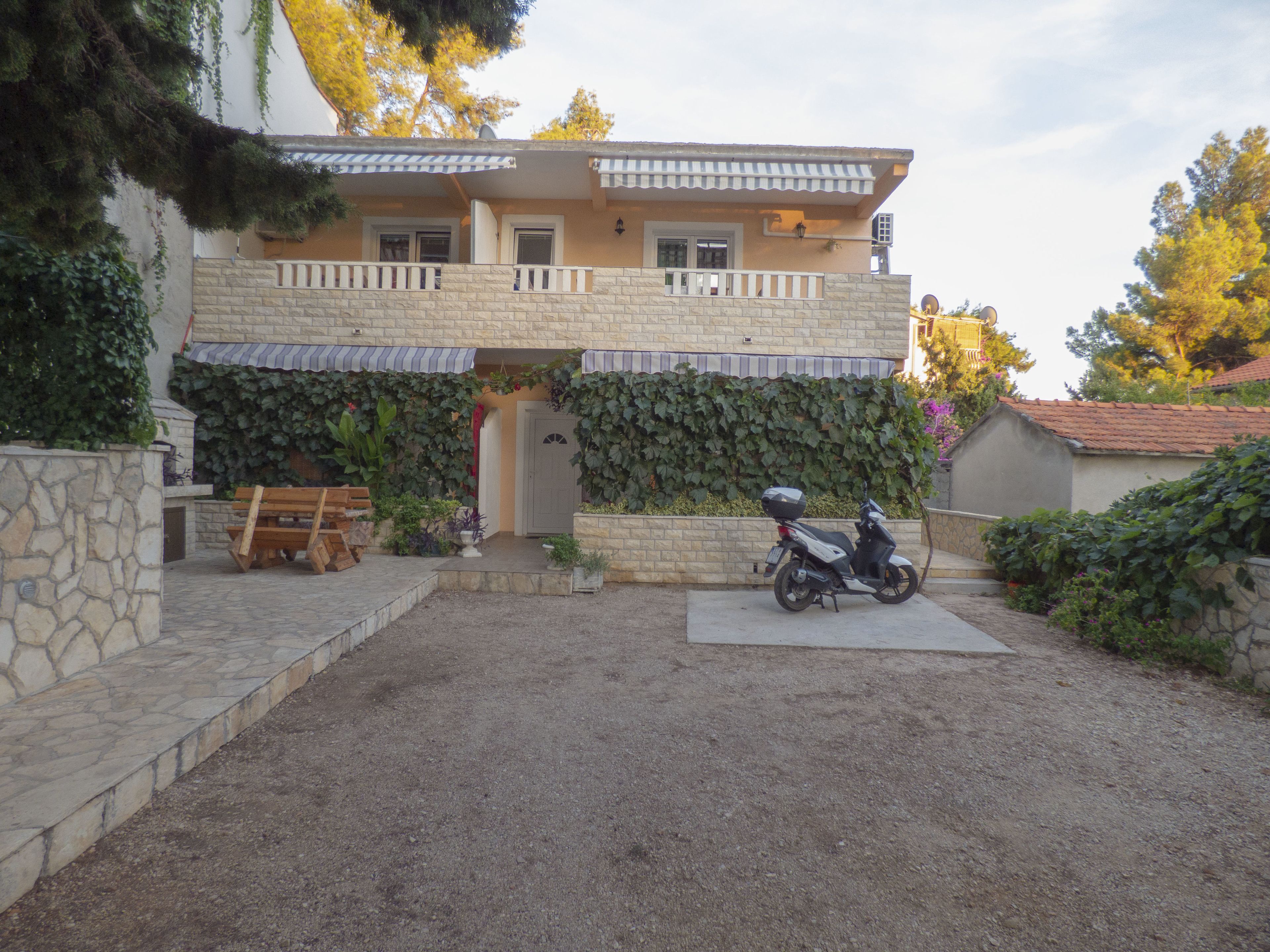 A two-story house with a stone facade, a balcony, and a covered porch area.