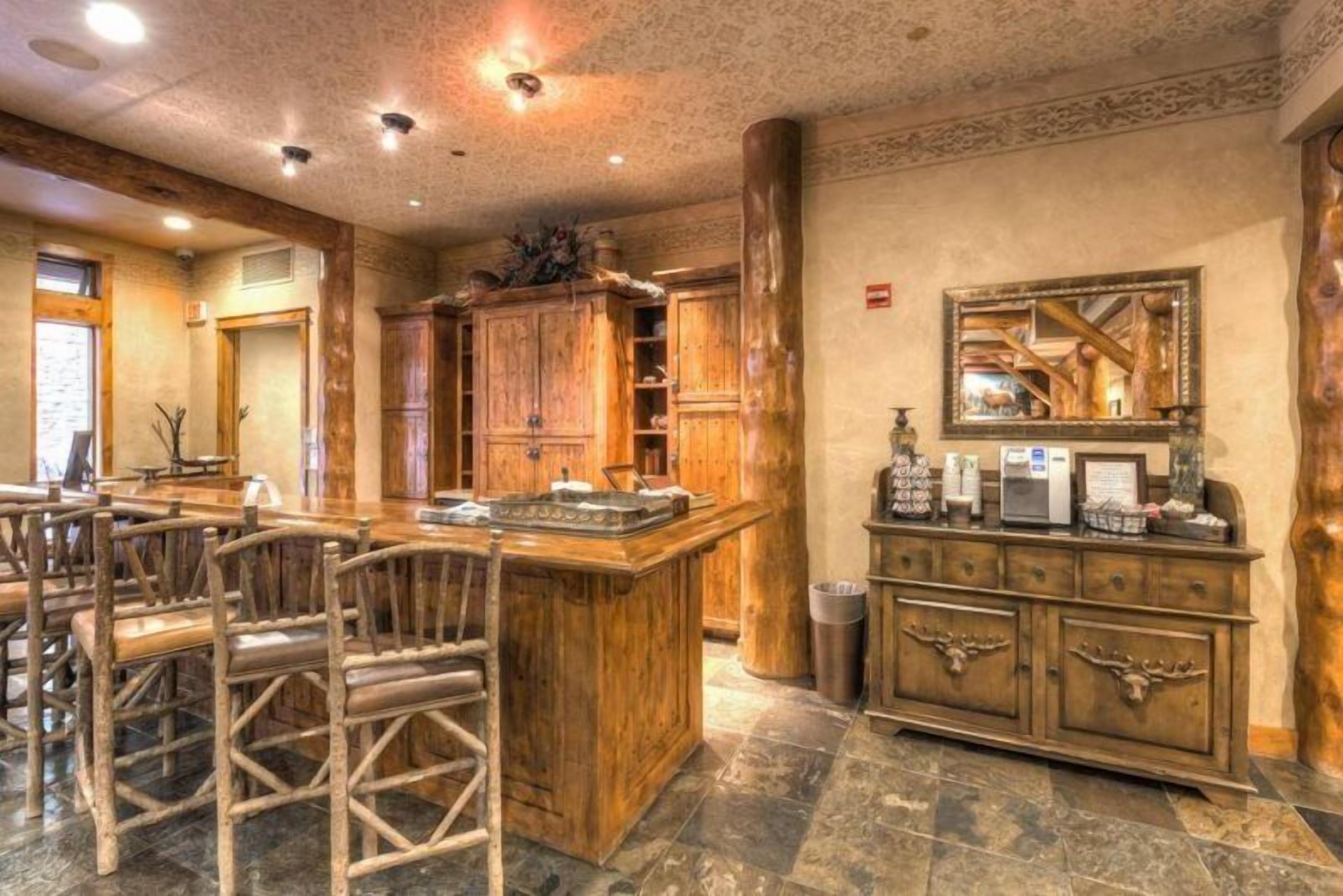 Un intérieur rustique avec des meubles en bois, un sol en pierre et une grande armoire en bois dotée d’un miroir.