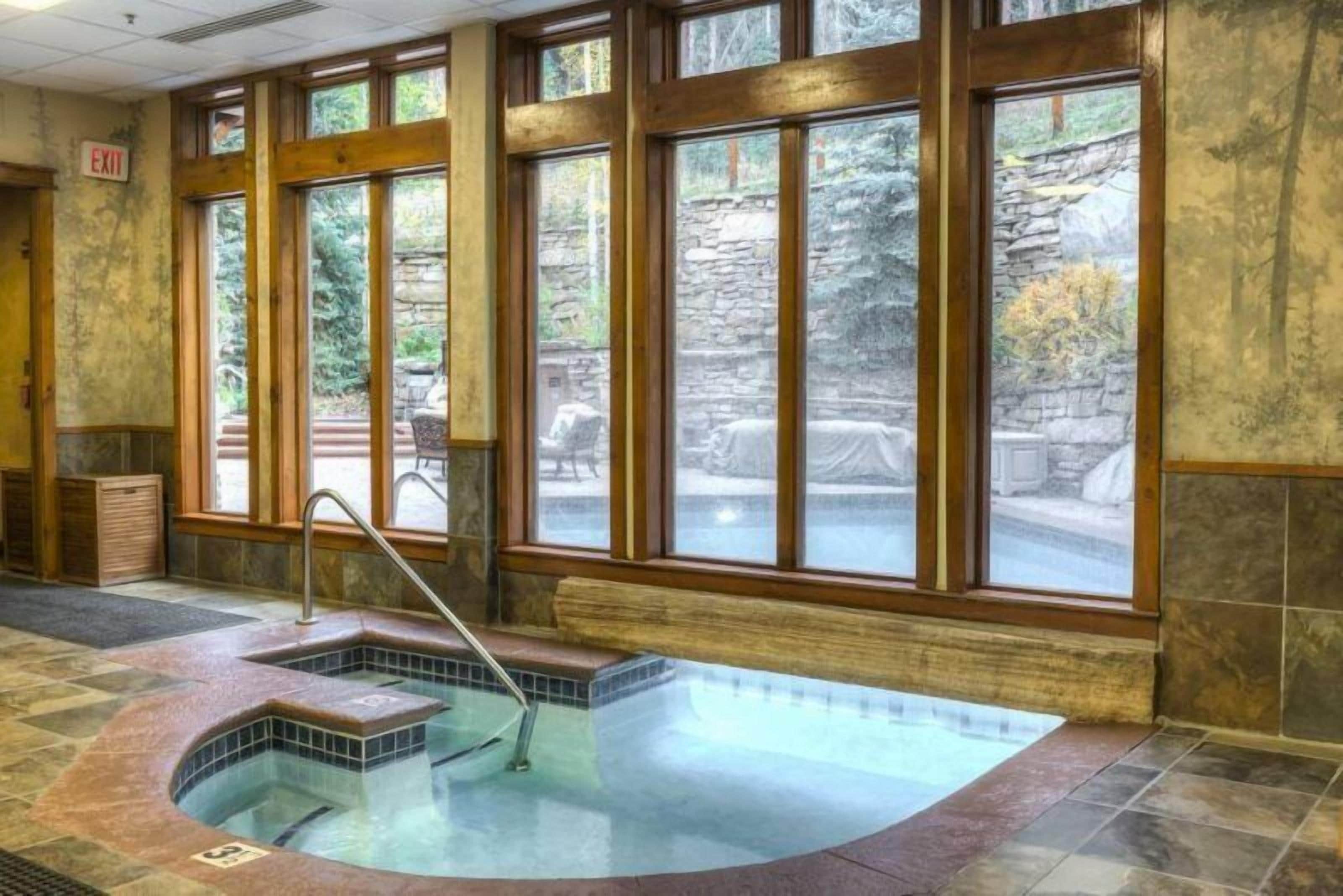 A spa area with a hot tub, large windows, and stone walls.