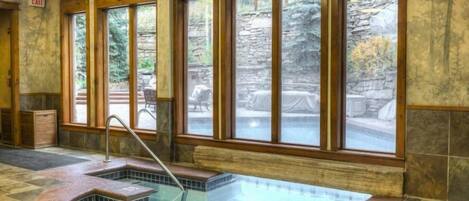 A spa area with a hot tub, large windows, and stone walls.