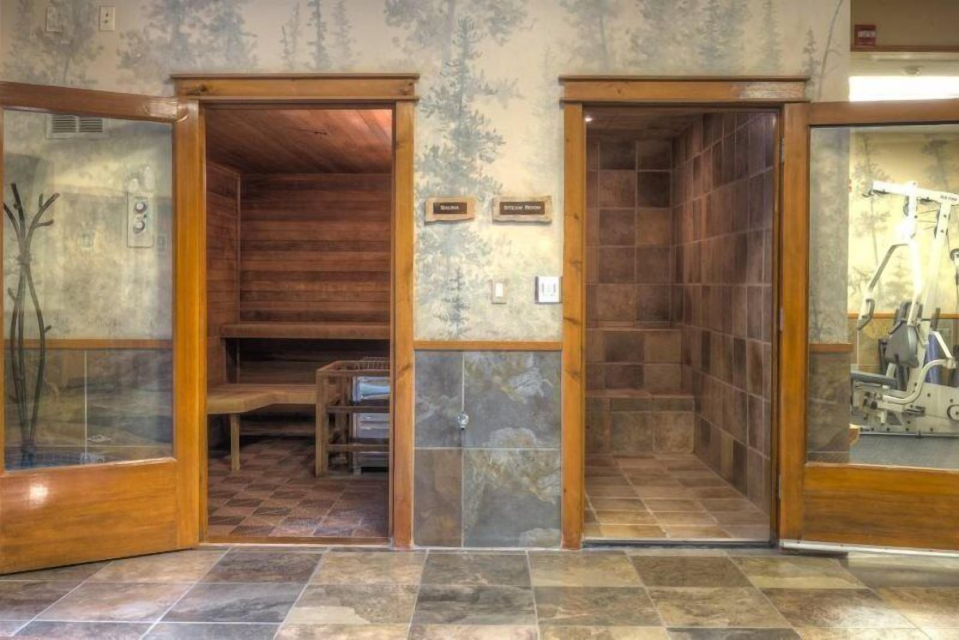 Ein Spa-Raum mit Holzwänden, Steinböden und einer Glastür.