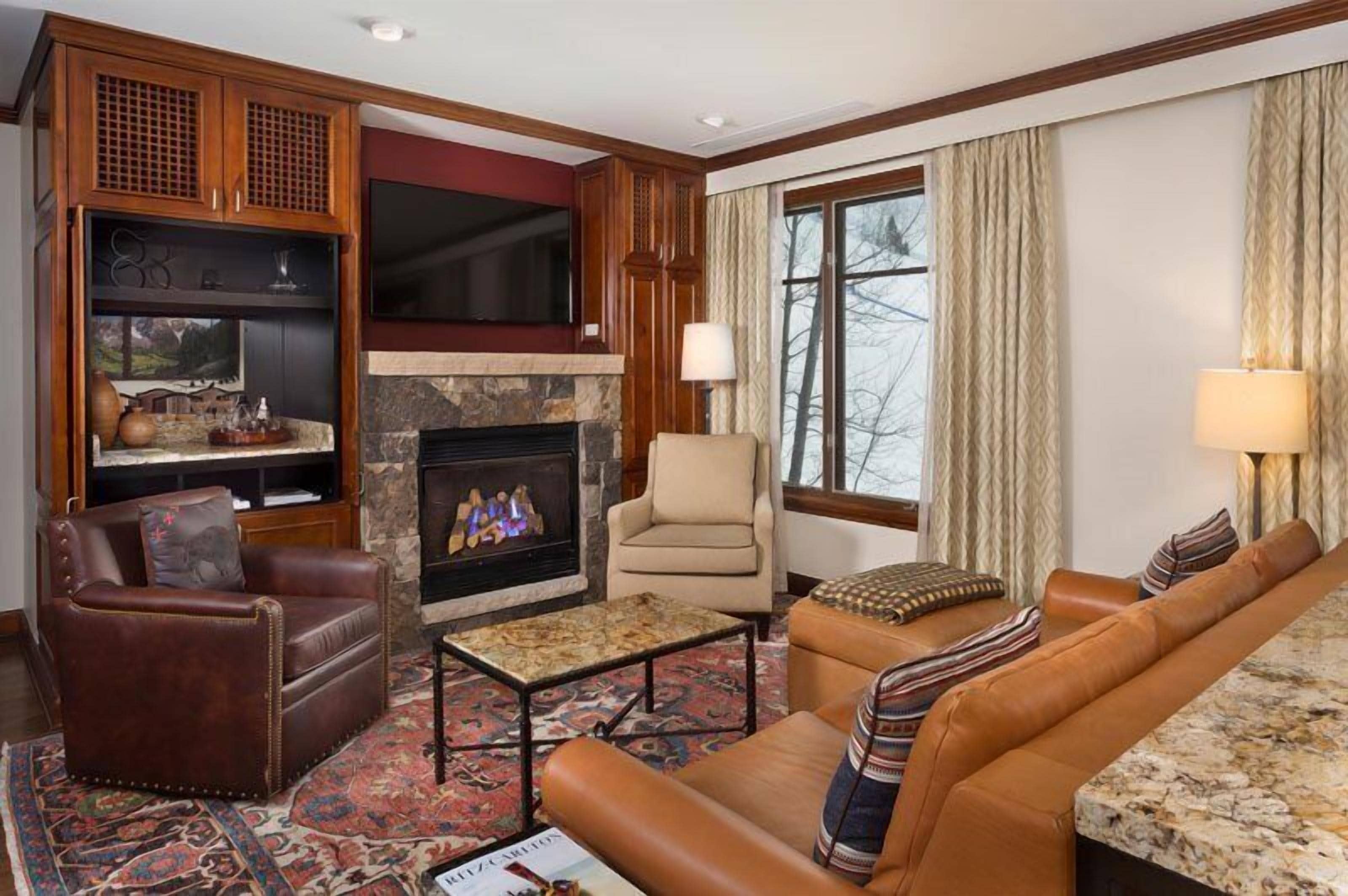 A living room with a fireplace, leather furniture, and a television.