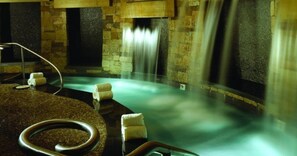 A spa area with a hot tub, stone walls, and a waterfall feature.