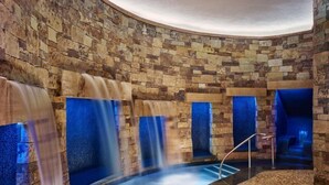 A spa area with stone walls, a central water feature, and seating areas.