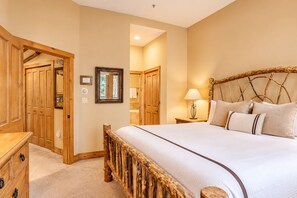 A bedroom with a large bed, wooden wardrobe, and a mirror on the wall. - 30577 The Timbers (Keystone)