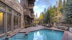 A pool area with stone walls, outdoor furniture, and a wooden deck. - 30577 The Timbers (Keystone)