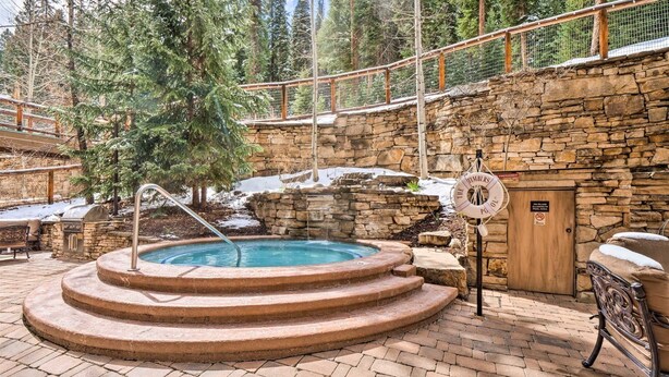 A hot tub with a stone wall and a wooden deck. - 30577 The Timbers (Keystone)