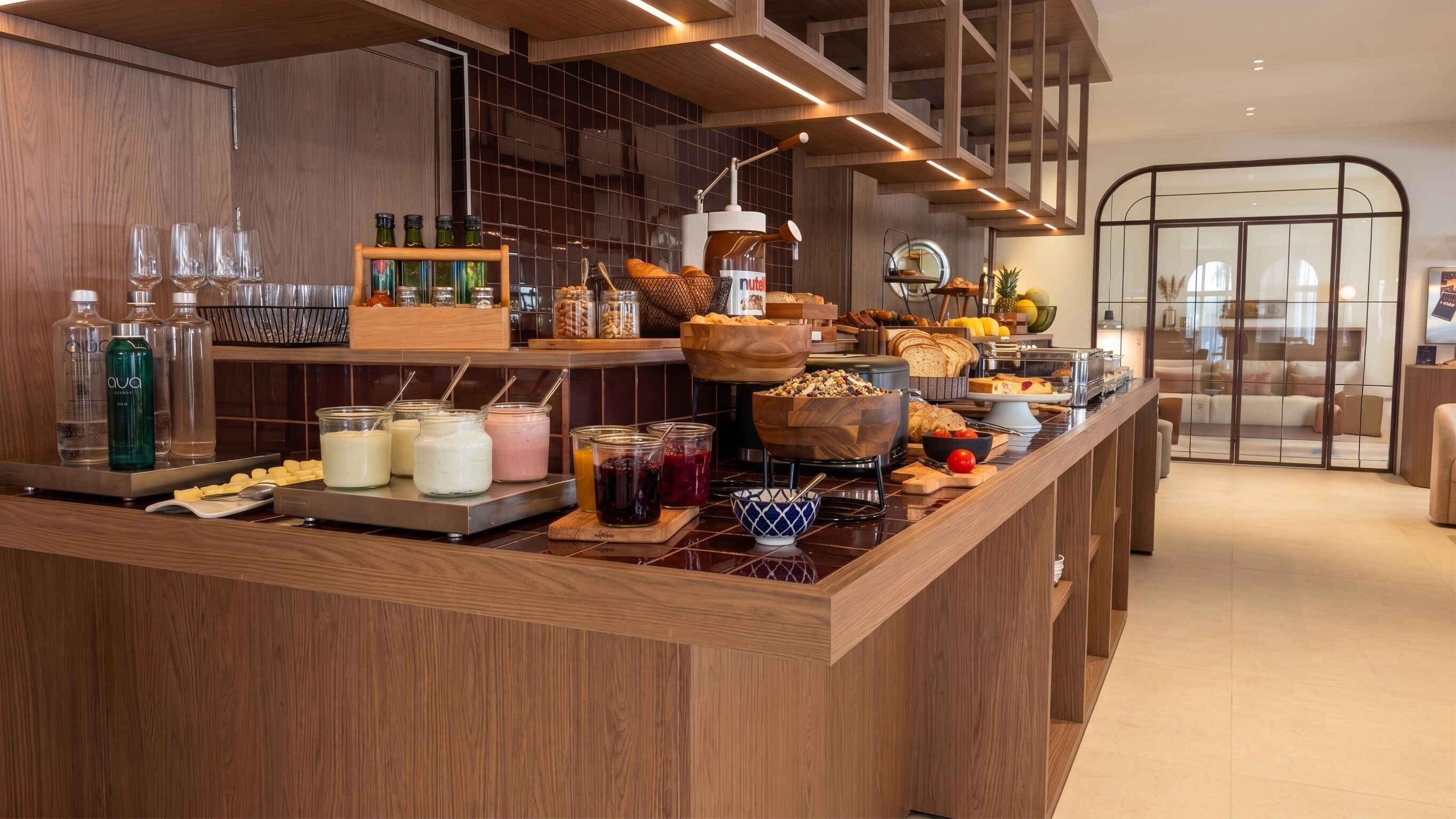 Un buffet pour le petit-déjeuner proposant divers aliments et boissons, notamment des pots de lait, du pain et un distributeur de Nutella.