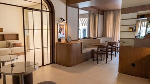 A modern hotel room with a sofa, a round table, a desk, and a mirror. - Hotel Medium Montecarlo  (Llafranc)