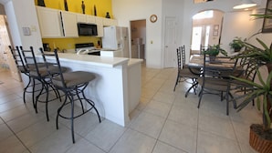 A kitchen with a central island, white cabinets, and a yellow accent wall. - 3BR 2BA Home in Rolling Hiils by CV-2616 (Kissimmee)
