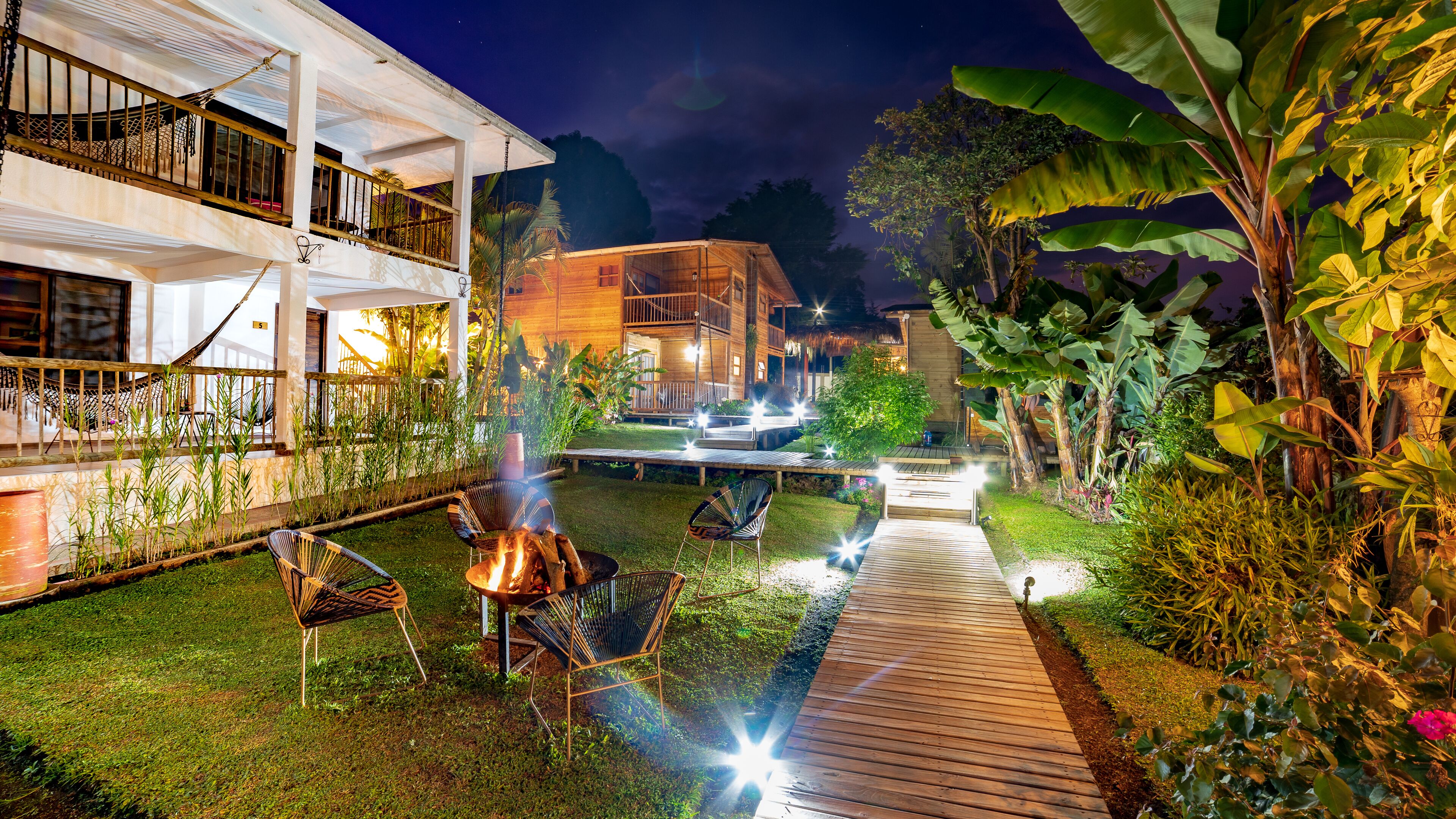 A well-lit outdoor area with a wooden deck, lounge chairs, and a barbecue grill.