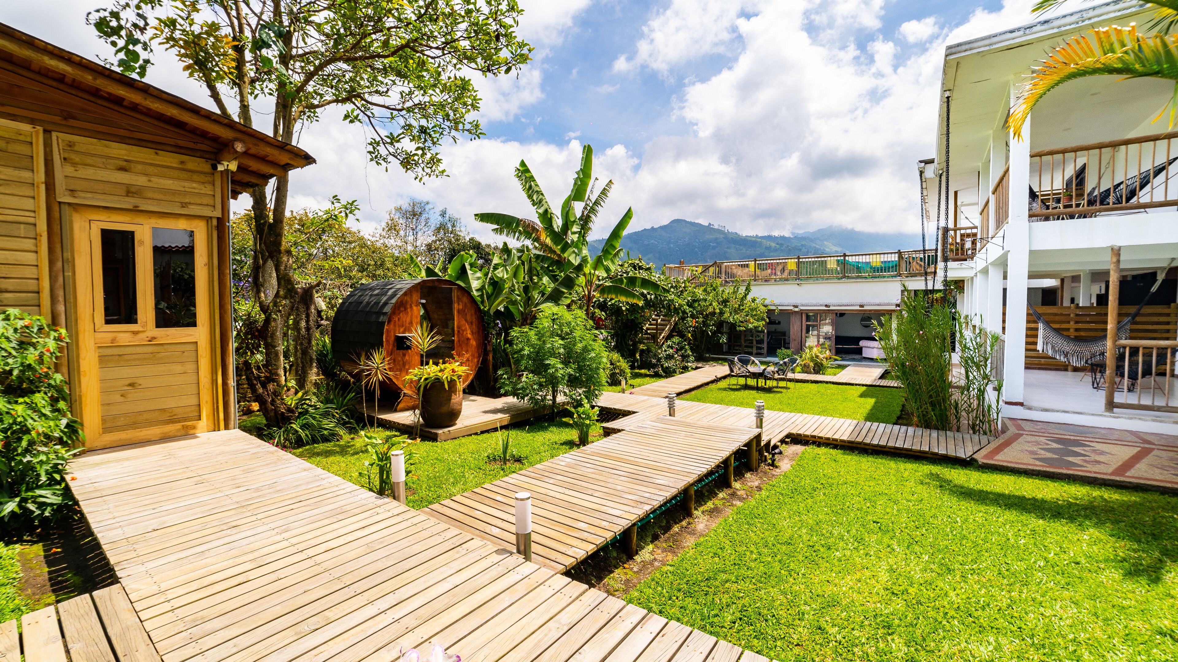 A wooden house with a large barrel, a grassy yard, and a wooden deck.