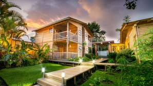 A two-story wooden house with a balcony, surrounded by lush greenery and a wooden deck. - Hotel Terasu Salento (Salento)