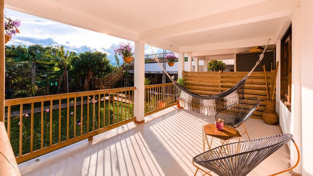A covered outdoor area with a wooden deck, a hammock, and a seating area with a table and chairs. - Hotel Terasu Salento (Salento)