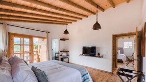 A bedroom with a large bed, wooden ceiling beams, a television, and a view of the outdoors. - Hotel Terasu Salento (Salento)