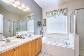 A bathroom with a double sink vanity, a large mirror, a bathtub, and a shower enclosure. - 3BR 2BA Home in Windsor Palms by CV-8168 (Kissimmee)