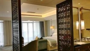 Une chambre d’hôtel avec un lit, un bureau, une chaise et un grand miroir.