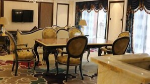 Un coin repas avec une table et des chaises en marbre, un lustre et un téléviseur fixé au mur.