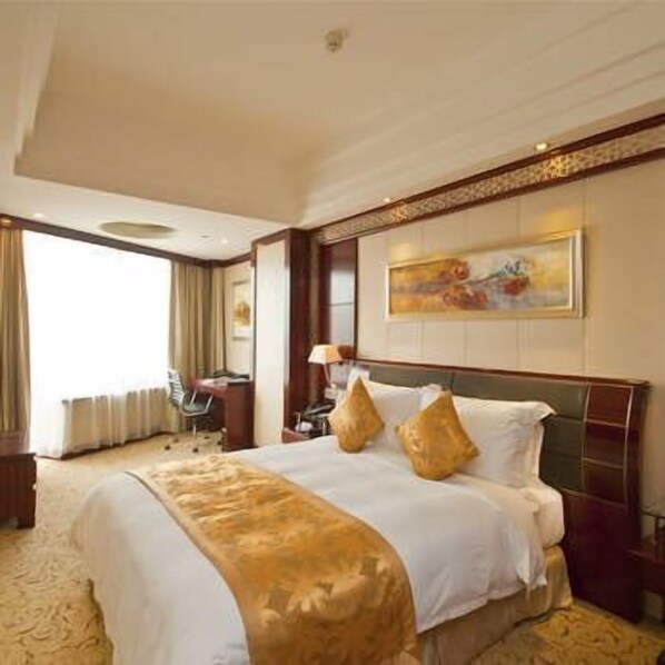 Una habitación de hotel con una cama grande, un escritorio y una silla.