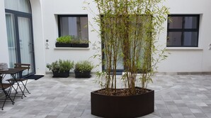 A modern building with a tiled floor, a large central plant, and a seating area with a table and chairs. - Design Central Apartment (Bergamo)
