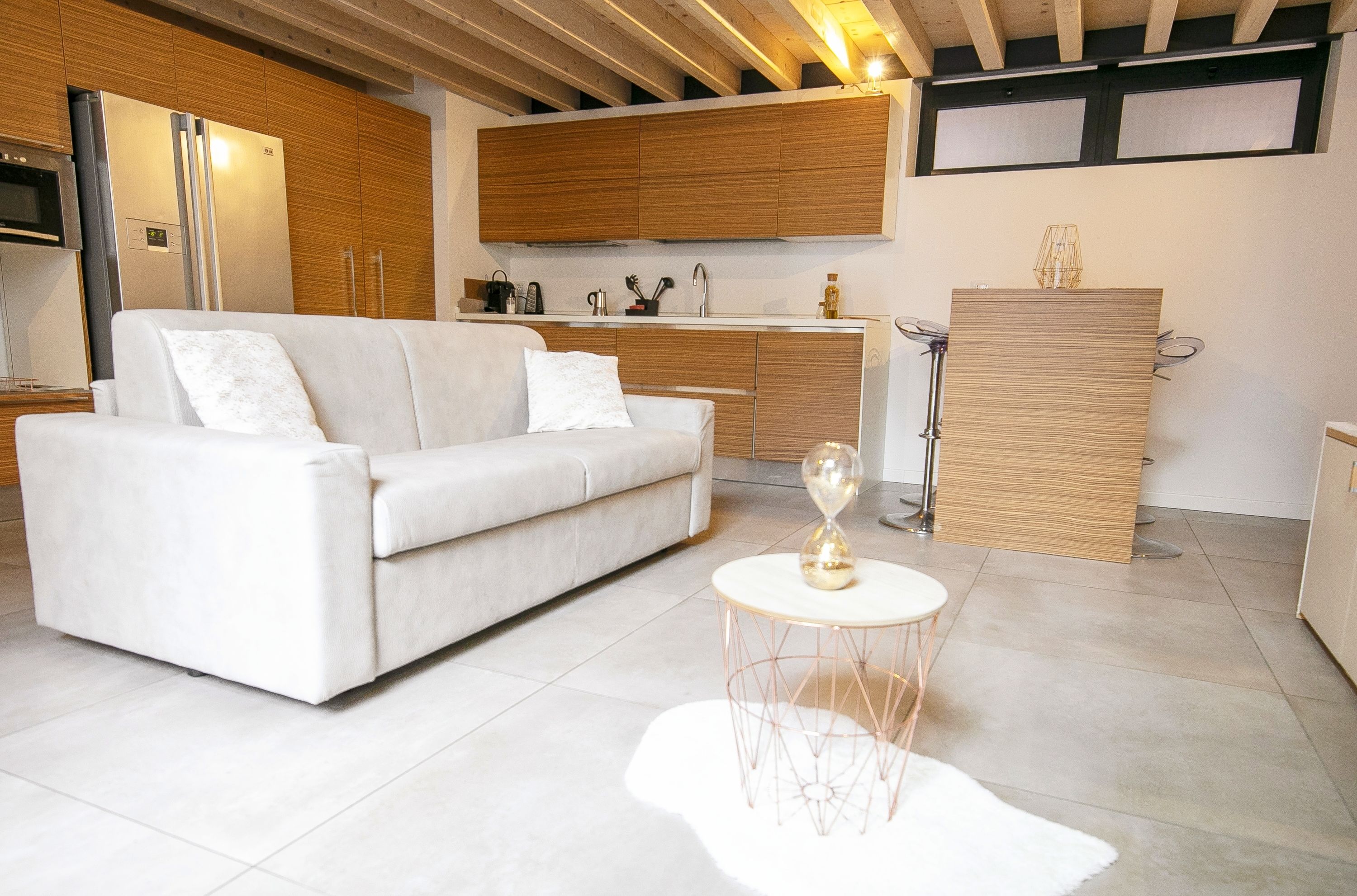 A modern kitchen with wooden cabinets, a white sofa, and a round coffee table with a decorative glass object.