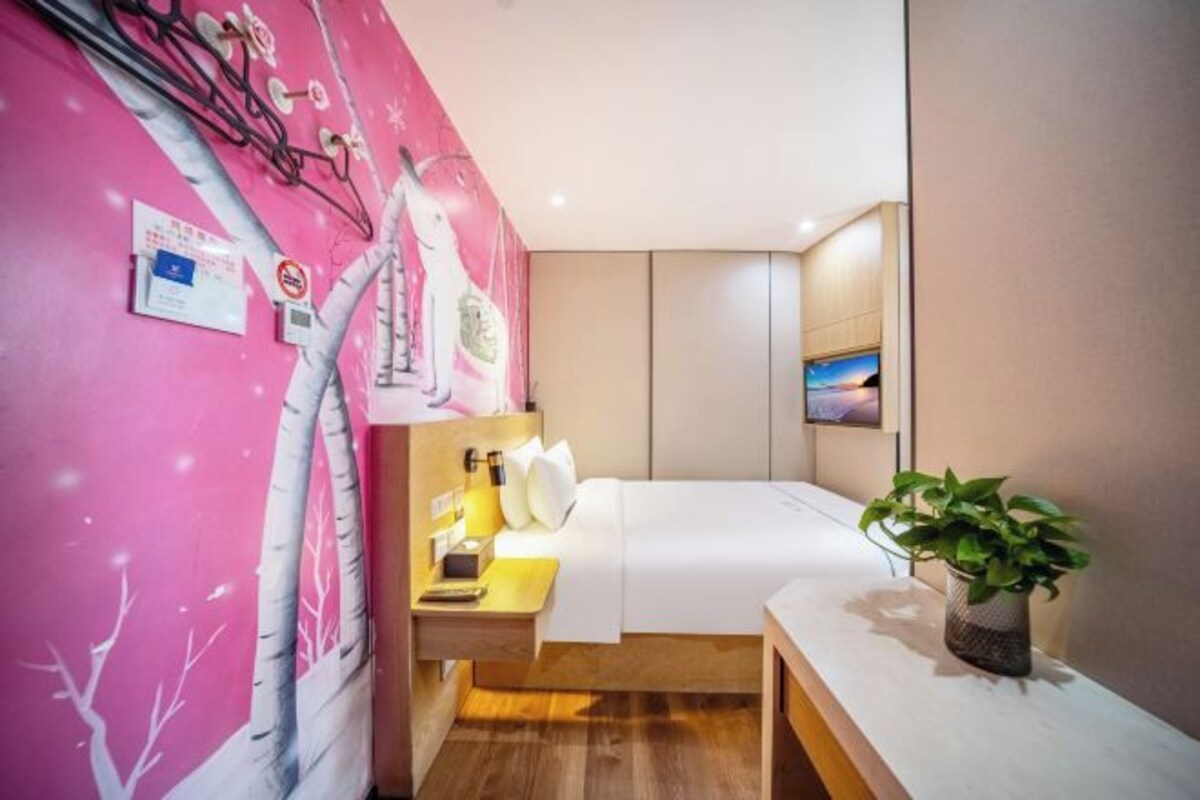 Une chambre à coucher avec un lit, une table de chevet, une lampe et un téléviseur fixé au mur.