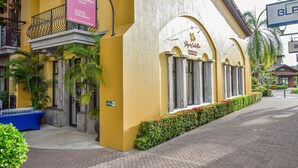 A hotel with a yellow facade, a balcony with black railings, and a signboard advertising 'Stay in Costa Rica'. - Los Suenos Resort Veranda 3G  (Jacó)