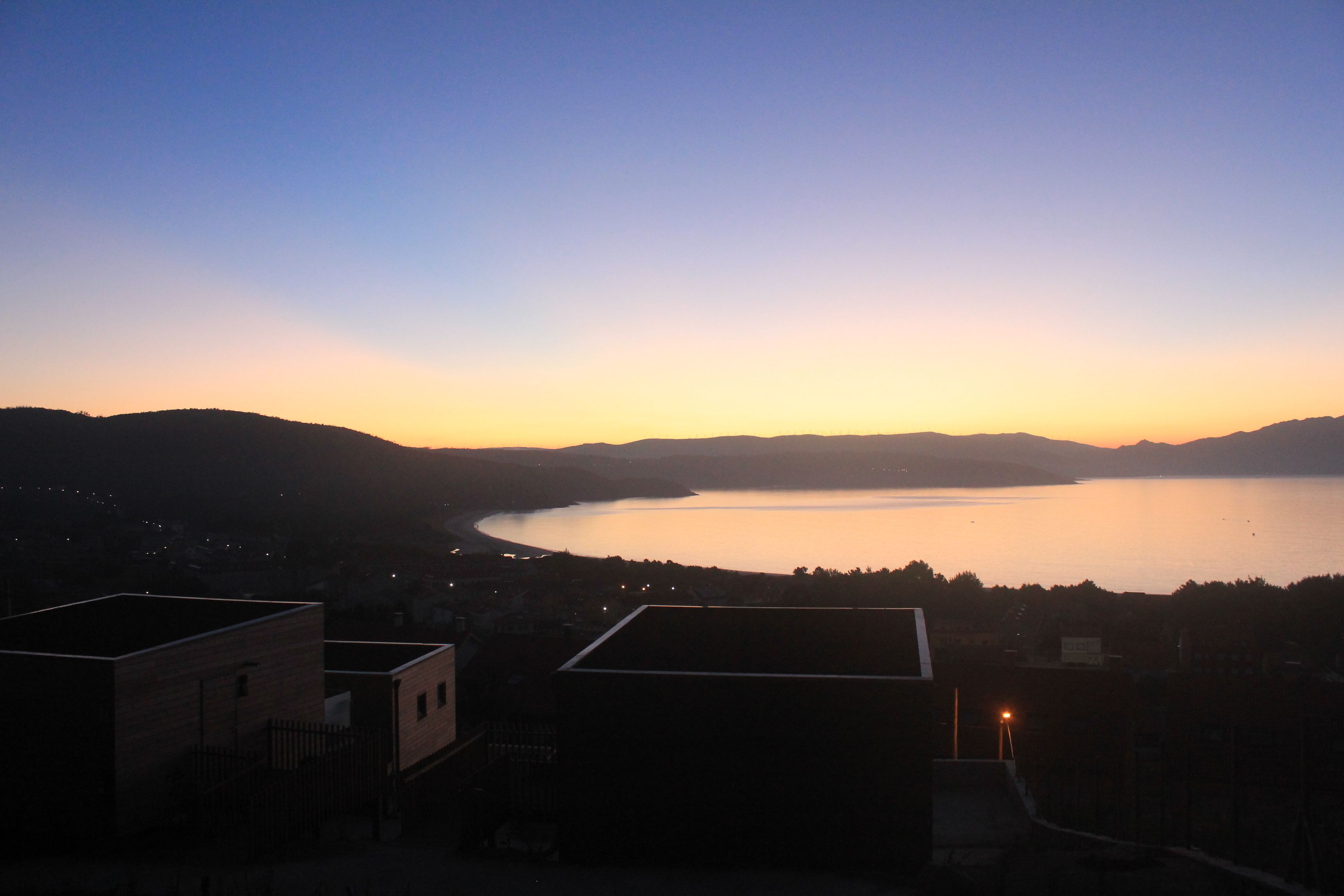 Vista de un lago al anochecer, con edificios en primer plano.